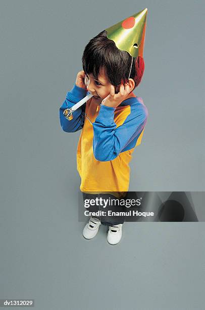 elevated view of a young boy with a party hat and a blowout and his hands over his ears - hands over ears stock pictures, royalty-free photos & images