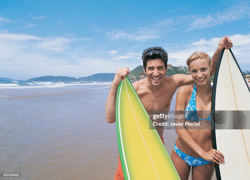 Portrait of a Young Couple Standing on a Beach in Summer With their Surfboards