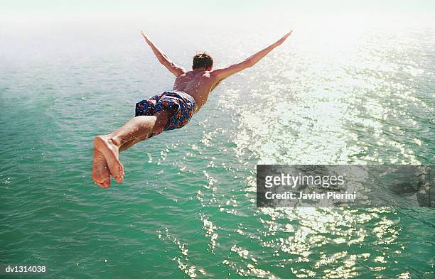 rear view of a man diving into the sea - courage photos et images de collection