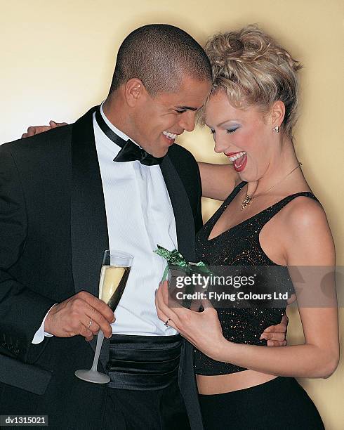 man holding a glass of champagne giving a gift to a surprised woman - sektempfang stock-fotos und bilder