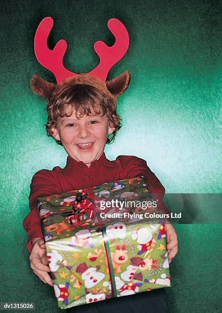 portrait of a boy holding a present wearing a festive deely bopper - deely bopper stock pictures, royalty-free photos & images