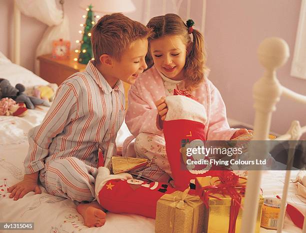 brother and sister opening presents from their christmas stockings on christmas morning - opening celebration of gregory colberts ashes and snow exhibition arrivals stockfoto's en -beelden