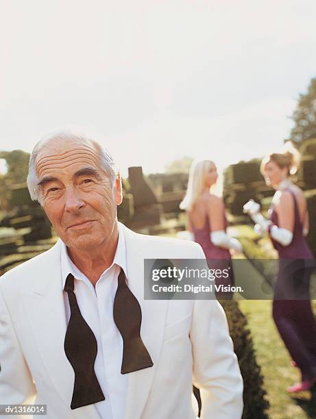 portrait of a senior man walking in a formal garden with women in the background - untied stock pictures, royalty-free photos & images