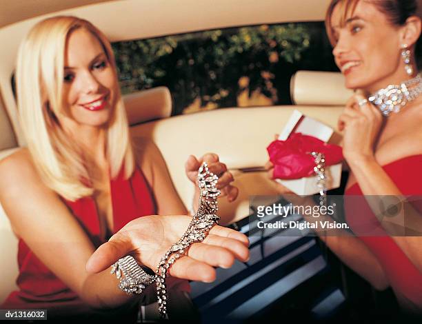young glamorous women sitting in the back of car holding jewellery - símbolo de status imagens e fotografias de stock
