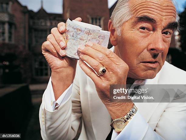 portrait of a senior man holding a wad of money - selbstverliebt stock-fotos und bilder