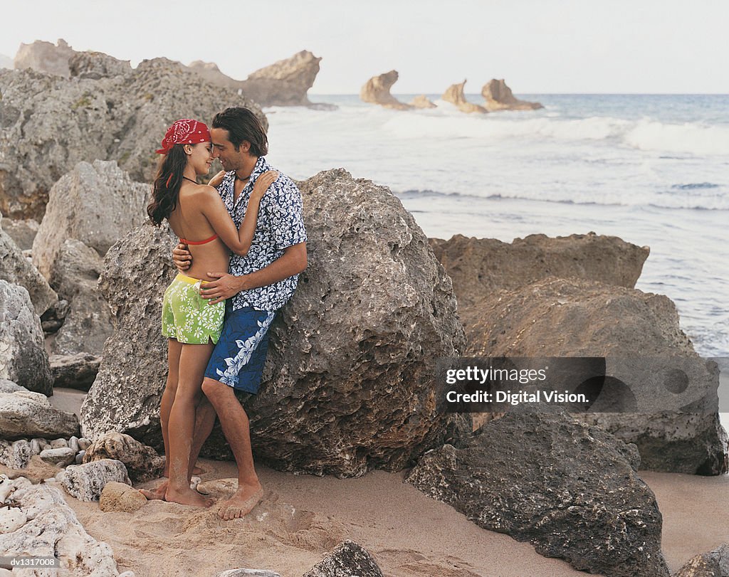 Passionate Young Couple Embracing on a Beach Secluded By Rocks