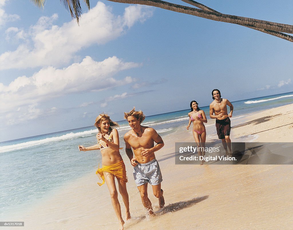 Four Young People Running on a Paradise Beach