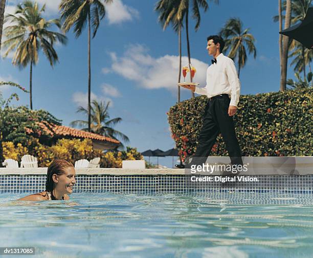 woman swimming in a pool with a waiter carrying a tray of cocktails in the background - platter side bildbanksfoton och bilder