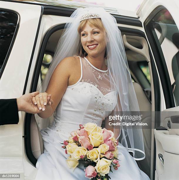 bride holding a bouquet of roses and getting out of a car - tiara stock-fotos und bilder