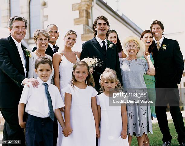 portrait of a bride and groom with their family standing outside of a church - married church stock pictures, royalty-free photos & images