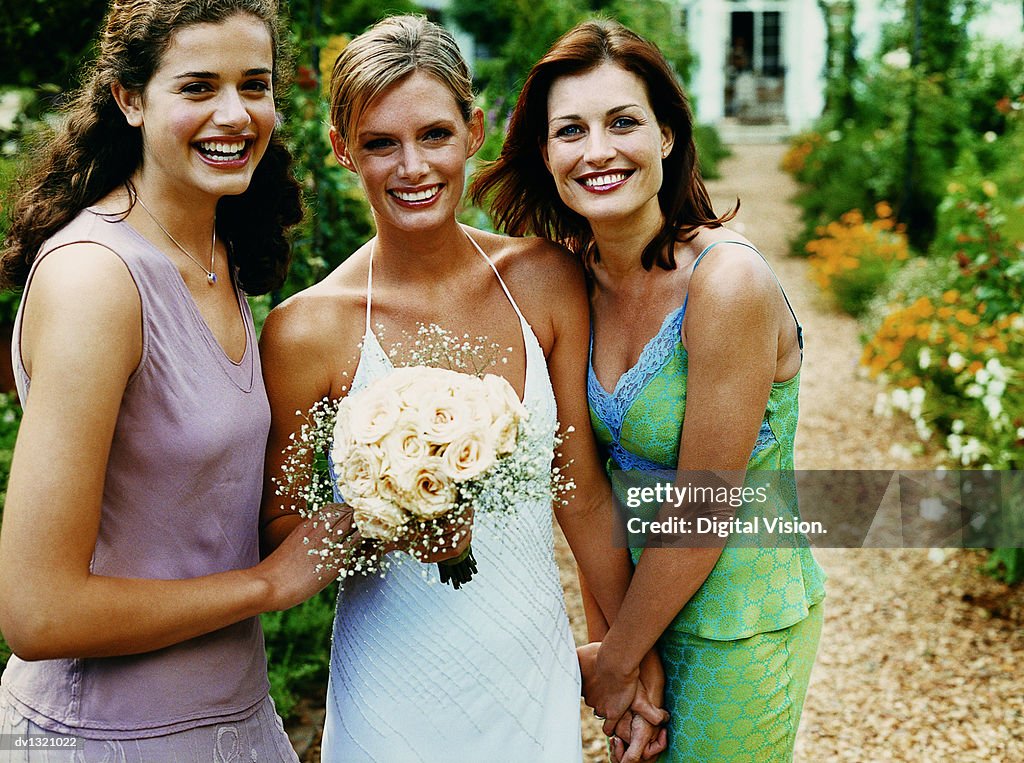 Portrait of a Bride Holding a Bouquet of White Roses Standing Between Her Two Bridesmaids