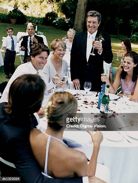 father giving a speech to the bride and groom at a wedding reception in a garden - mother and daughter smoking - fotografias e filmes do acervo