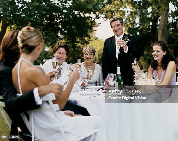 father giving a proposing a toast to the bride and groom at a wedding reception in a garden - bride father stock pictures, royalty-free photos & images