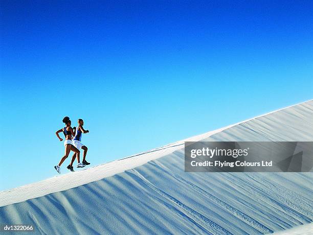 couple jogging up a steep sand dune - couple dunes stockfoto's en -beelden