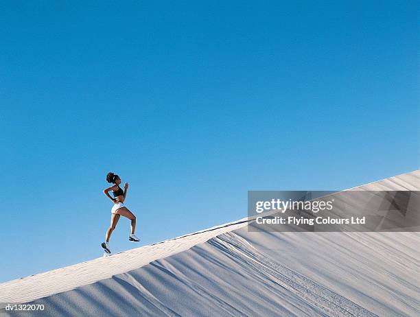 woman jogging up a sand dune - steep stock pictures, royalty-free photos & images