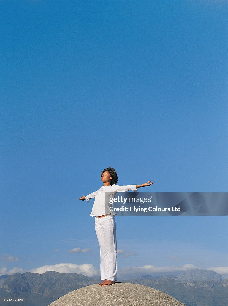 Woman Standing on Boulder With Arms Outstretched