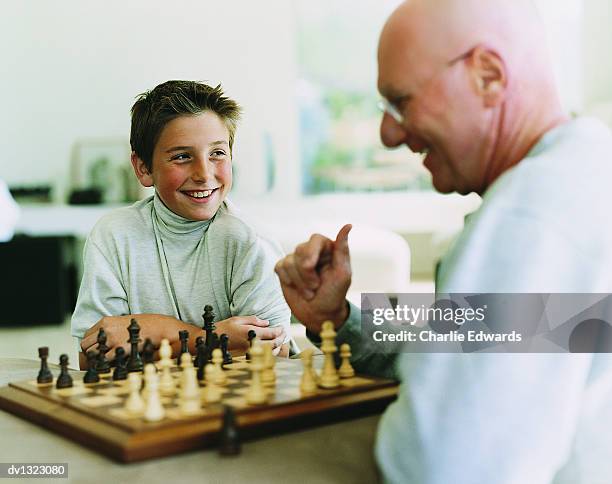 boy playing chess with his grandfather - jury loisirs photos et images de collection