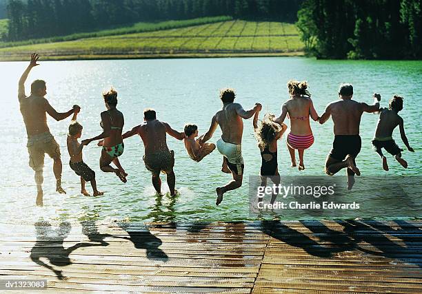 rear view of a large family group jumping in a lake together - agua estancada fotografías e imágenes de stock