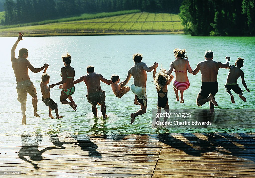 Rear View of a Large Family Group Jumping in a Lake Together