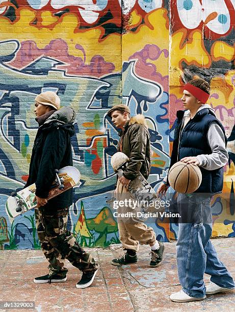 three teenage boys walking in an urban setting with skateboards, a basketball and attitude - basketball close up stock pictures, royalty-free photos & images