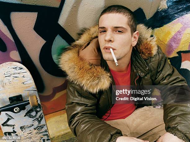 teenage boy crouching in an alley smoking a cigarette - anti smoking bildbanksfoton och bilder