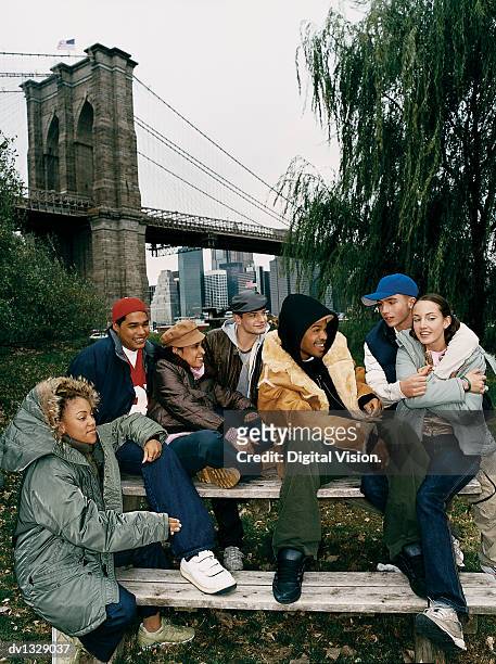 medium group of teenagers sitting on a bench in a park - medium group of people foto e immagini stock