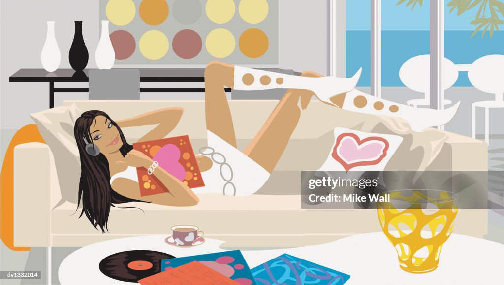 Portrait of a Young Woman Lying on a Sofa in a Living Room Listening to Music