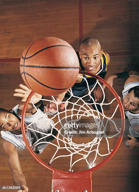basketball falling through a hoop with the players looking up - basketball team stock pictures, royalty-free photos & images