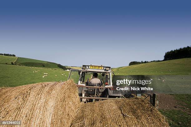 farmer driving a tractor and towing hay bales on a trailer in a field - trailer stock pictures, royalty-free photos & images