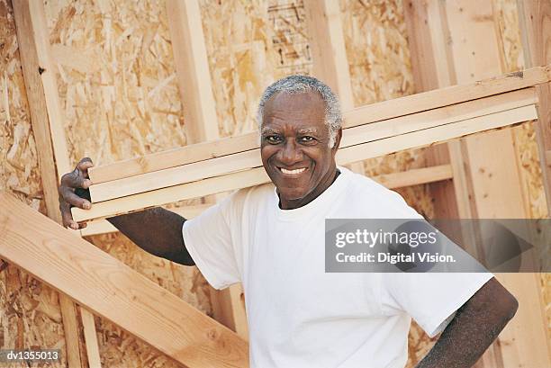 portrait of a man carrying planks of wood and a chipboard construction frame - wood frame ストックフォトと画像