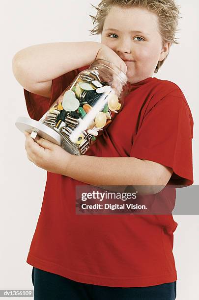 portrait of a fat young boy taking candy from a jar - candy jar stock pictures, royalty-free photos & images