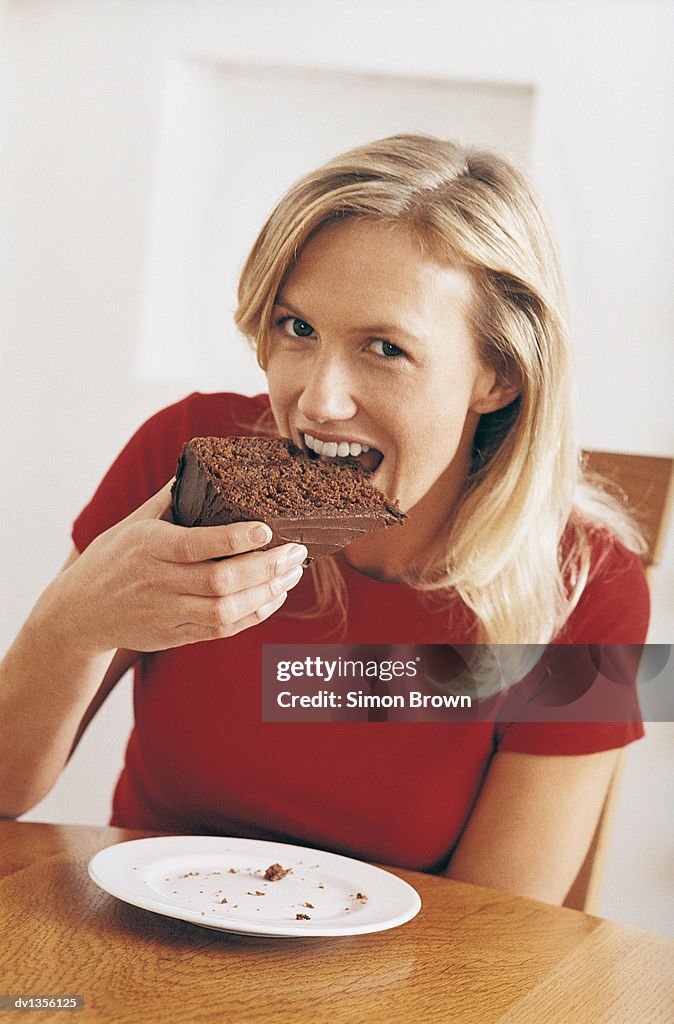 A Woman Eating a Large Slice of Chocolate Cake