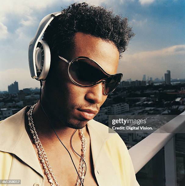 young man wearing listening to his personal stereo on a balcony with a cityscape in the background - personal stereo bildbanksfoton och bilder