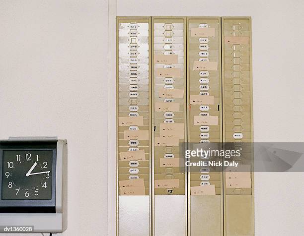 clockface next to a rack of clocking in time cards - clock on wall stock pictures, royalty-free photos & images