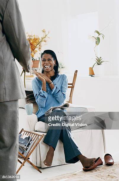 woman sitting in an armchair in her sitting room pleased at receiving a bouquet of orchids from a man - porta revistas - fotografias e filmes do acervo
