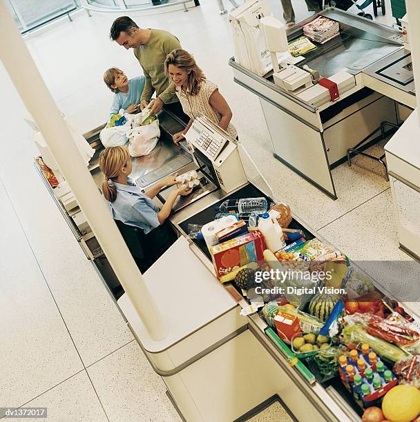 family of three buying groceries at a supermarket checkout - キャッシュレジスター ストックフォトと画像