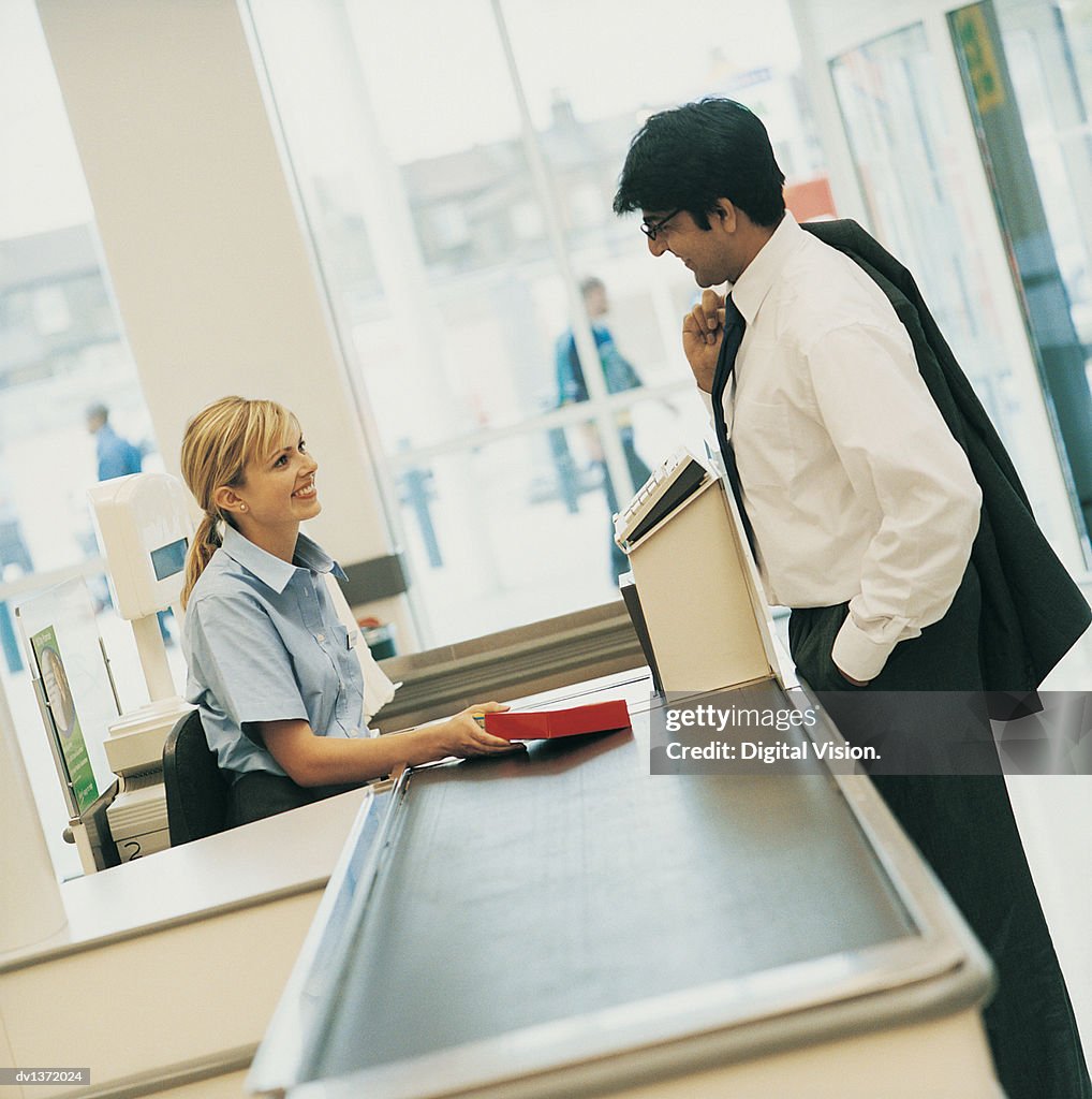 Man Buying Groceries at a Supermarket Checkout Counter