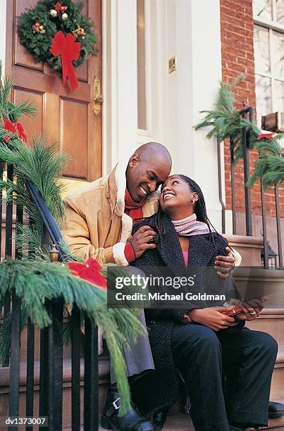 young man giving a christmas present to a woman sitting on  the front steps of a house at christmas - presents season 2 of kingdom at the 2015 tca summer press tour stockfoto's en -beelden