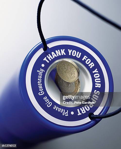 pound coins falling into the coin slot of a donation box - two pound coin stock pictures, royalty-free photos & images