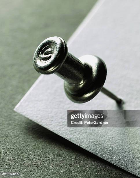 close up of the corner of a piece of paper pierced by a drawing pin - pin up fotografías e imágenes de stock