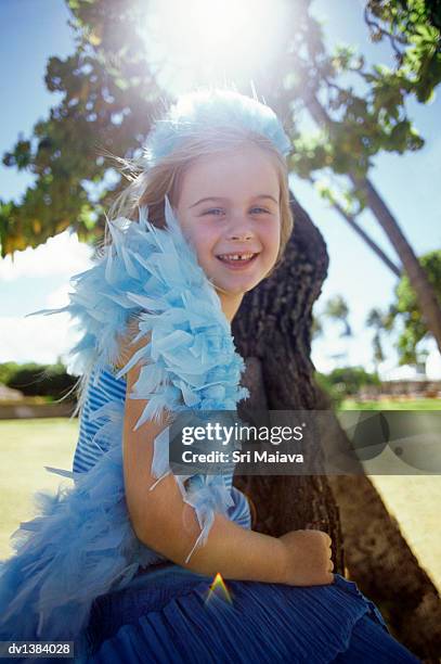 young girl wearing a feather boa sits on a tree trunk smiling at the camera - feather boa 個照片及圖片檔