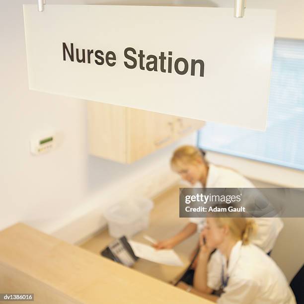two nurses working at a reception desk behind an information sign in a hospital - escrita ocidental imagens e fotografias de stock