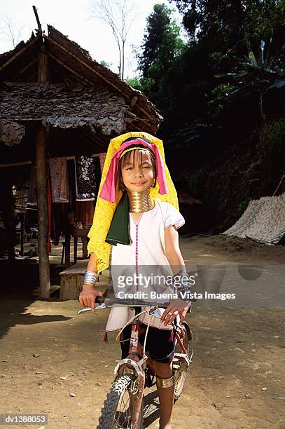 young padaung girl on a bicycle by a building, chiang mai, thailand - padaung tribe stock pictures, royalty-free photos & images