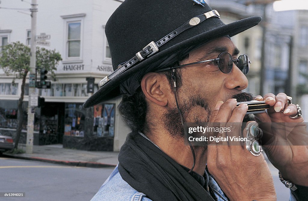 A Mature Man Plays the Harmonica in the Streets of Haight-Ashbury in San Francisco