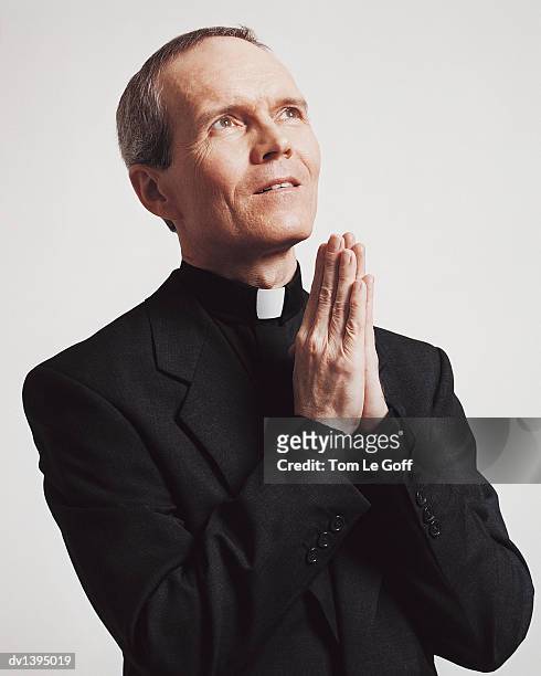 portrait of a priest praying with his hands together - habit stock-fotos und bilder