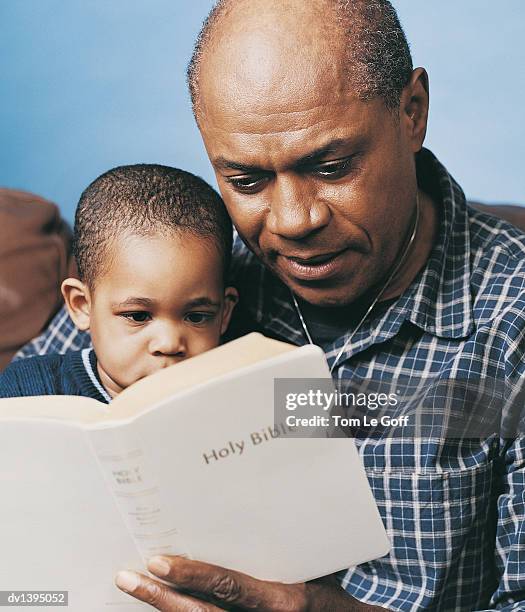grandfather and grandson reading bible together - godsdienstvrijheid stockfoto's en -beelden