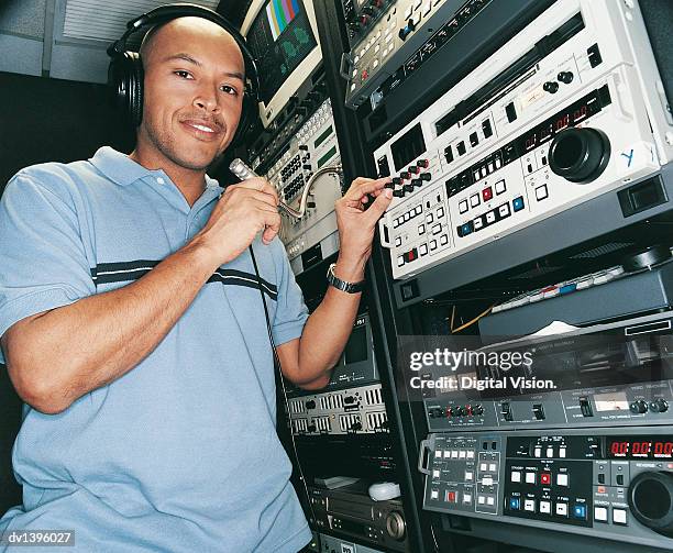 portrait of an engineer holding a microphone on editing equipment - editing equipment stock pictures, royalty-free photos & images