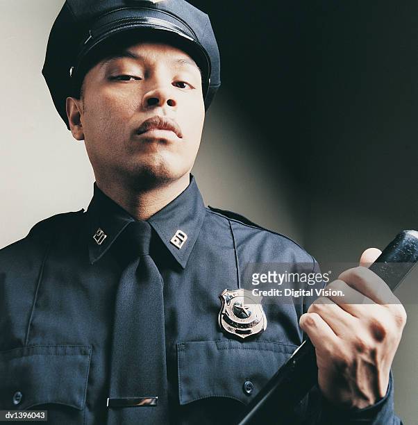 portrait of a male police officer holding a truncheon - emergency services equipment stock pictures, royalty-free photos & images