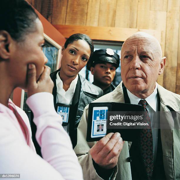 fbi agents approaching a woman in her home - female fbi stock pictures, royalty-free photos & images