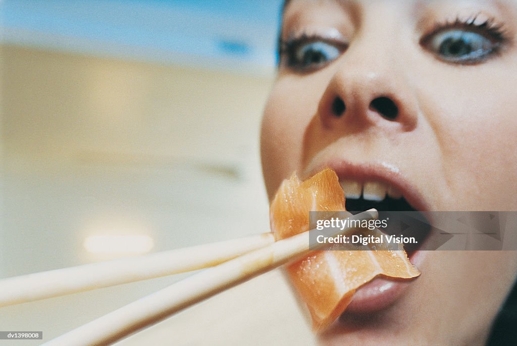 Close up of a Surprised Woman Eating a Piece of Sushi Using Chopsticks